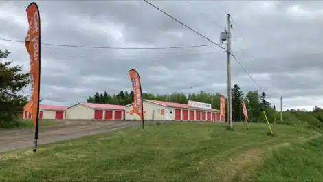 Front gate and bow flags promoting Mini Mall Storage Moncton Homestead rd.