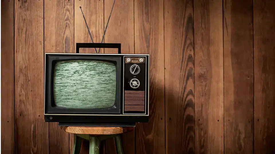 vintage CRT TV in front of a wood panel background