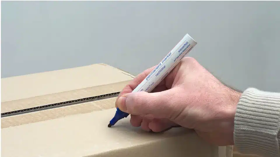 moving box with a person holding a sharpie poised to label it