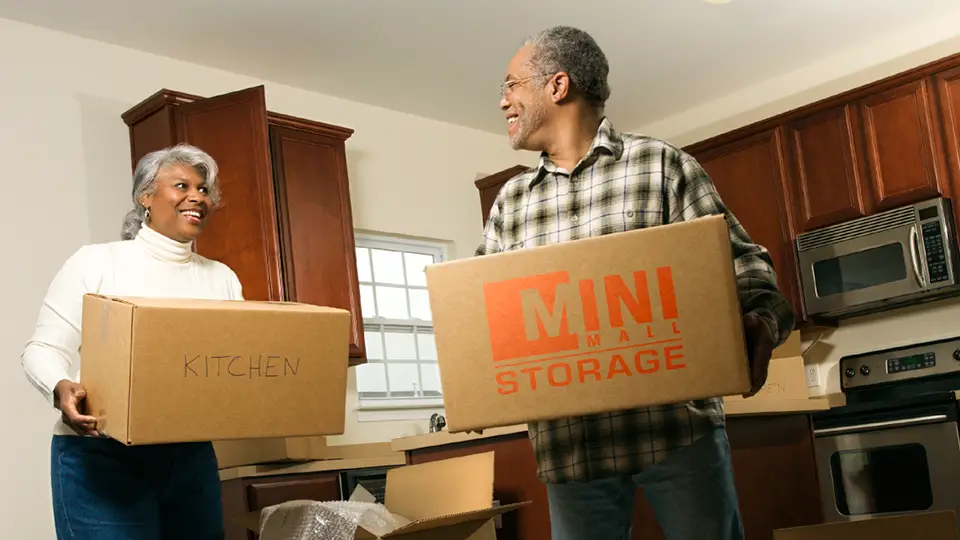 A couple packing their belongings to downsize their home with Mini Mall Storage boxes